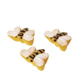 Drei Schwimmkerzen in Form von Bienen mit entsprechender Farbe